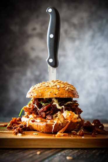 Pulled Pork Burger auf Holzbrett mit Messer