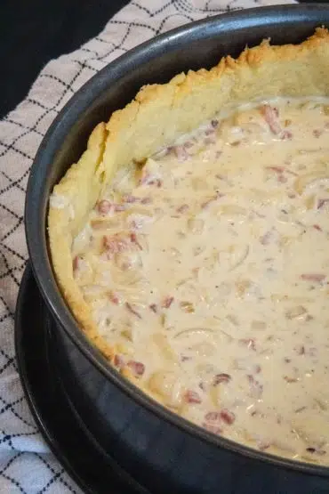 Der vorgebackene Quiche-Teig wird gefüllt