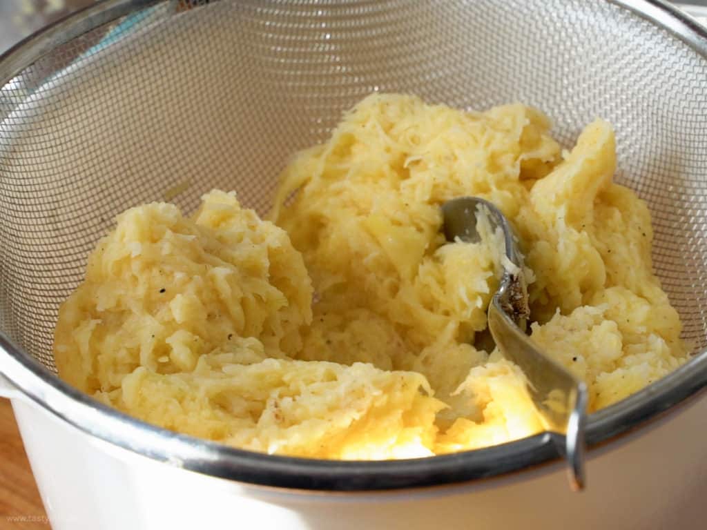 Kartoffelmasse in einem Sieb ausdrücken