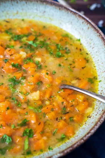 Ein Teller Karottensuppe mit Löffel