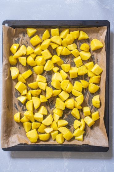 Kartoffeln für Patatas Bravas mit Salz und Öl auf einem Backblech