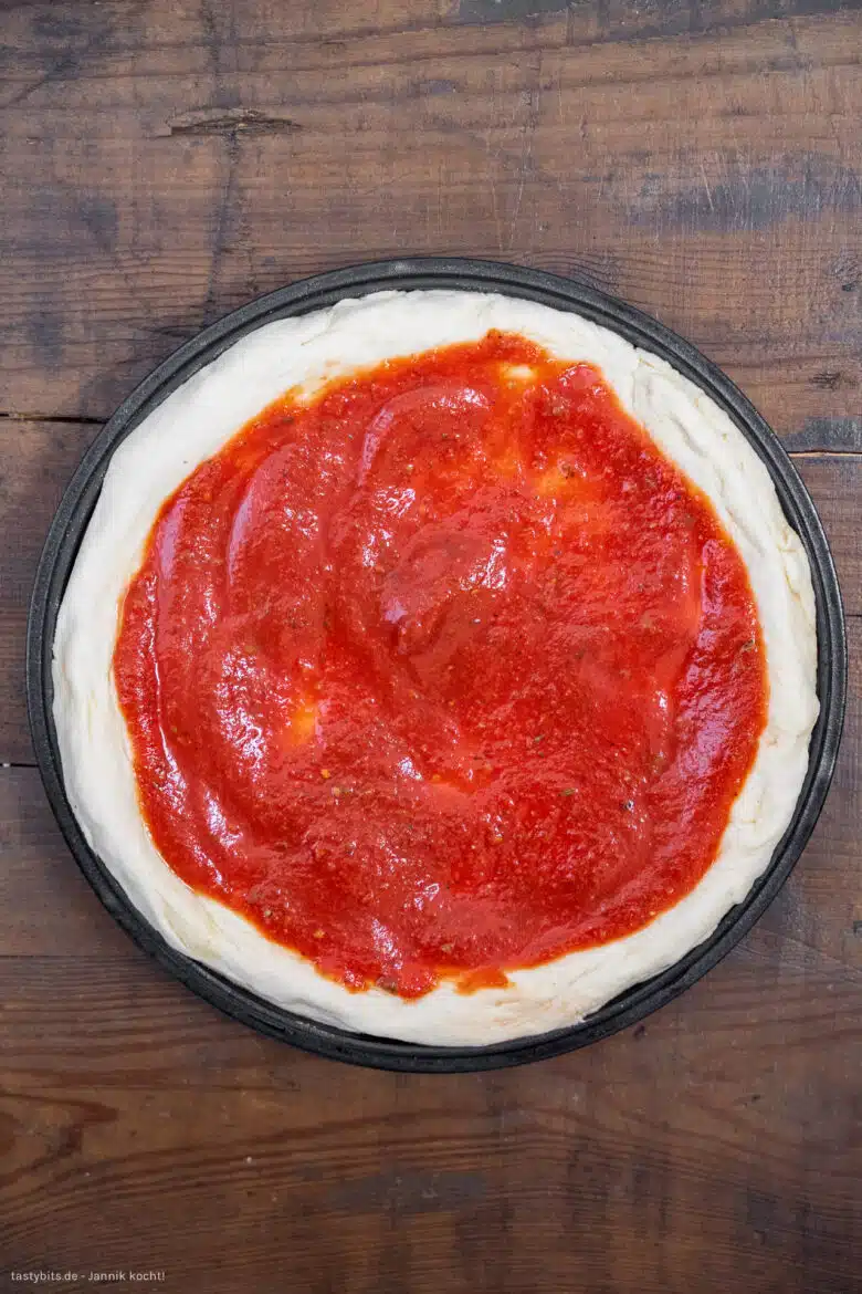 Pizza mit Tomatensauce bestreichen